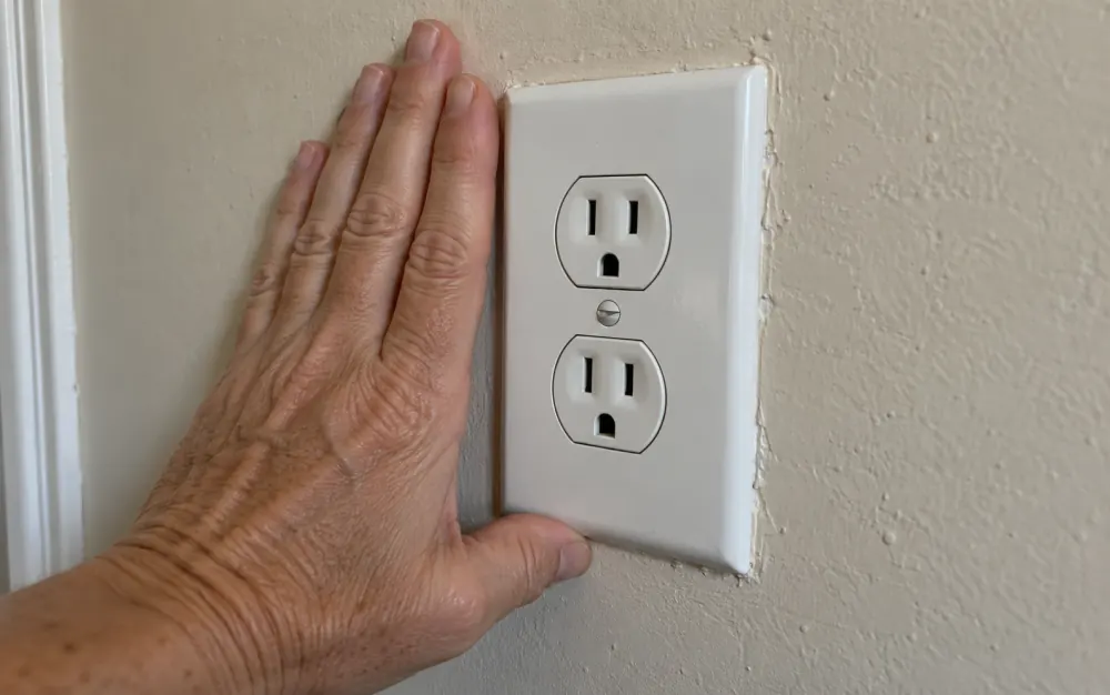 A hand resting against an outlet plate.